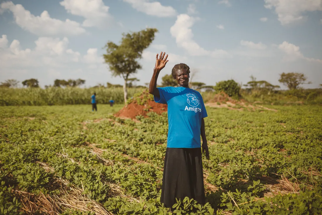 A farmer waving in a green field